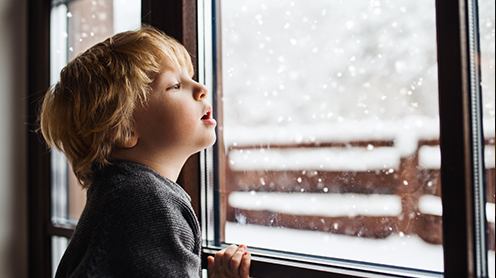 Young child watching snow fall from the window