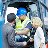 worker in forklift with man and woman looking in cabin